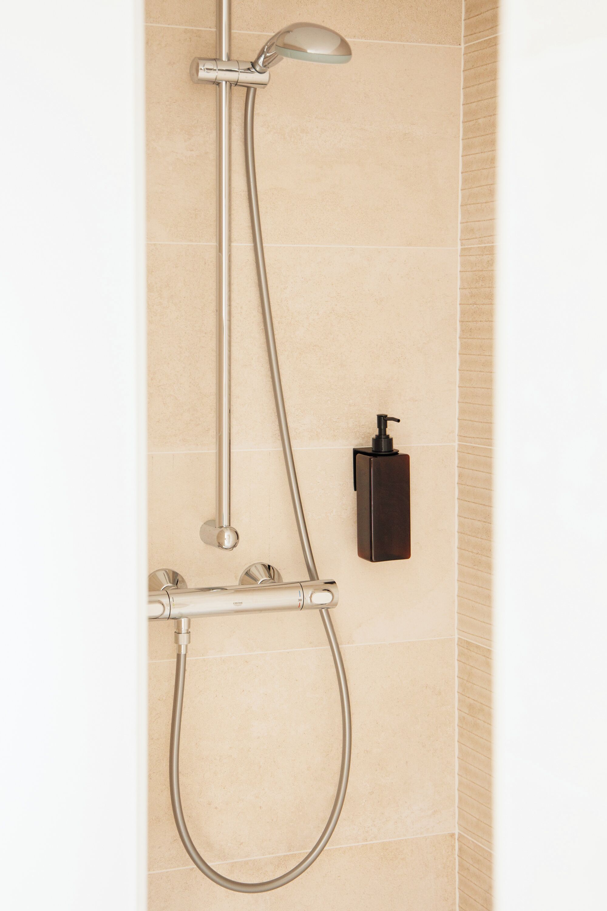 A wall-mounted shower with a handheld showerhead and a handheld hose.