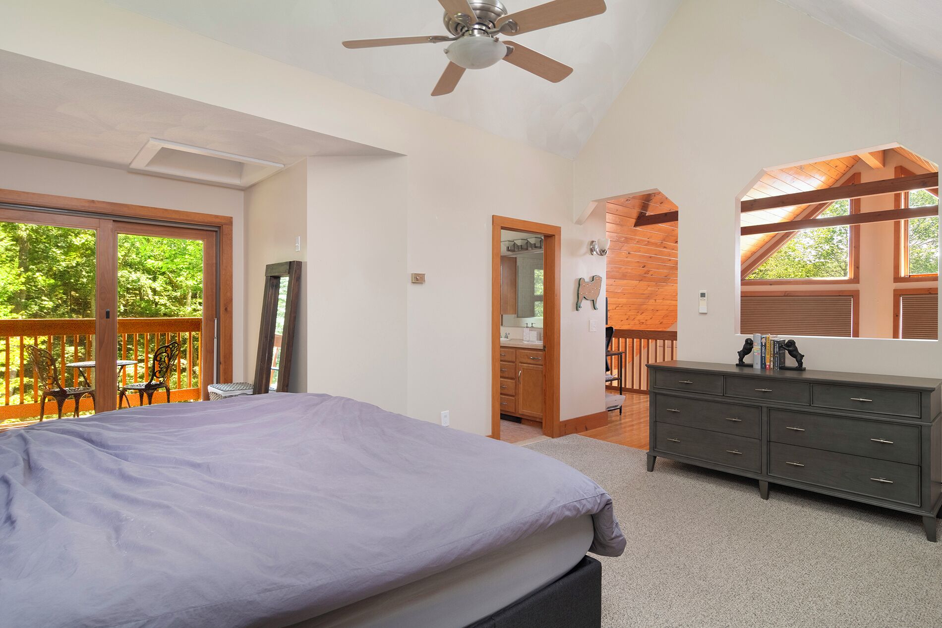 A bedroom with a bed, dresser, and a balcony with outdoor furniture.