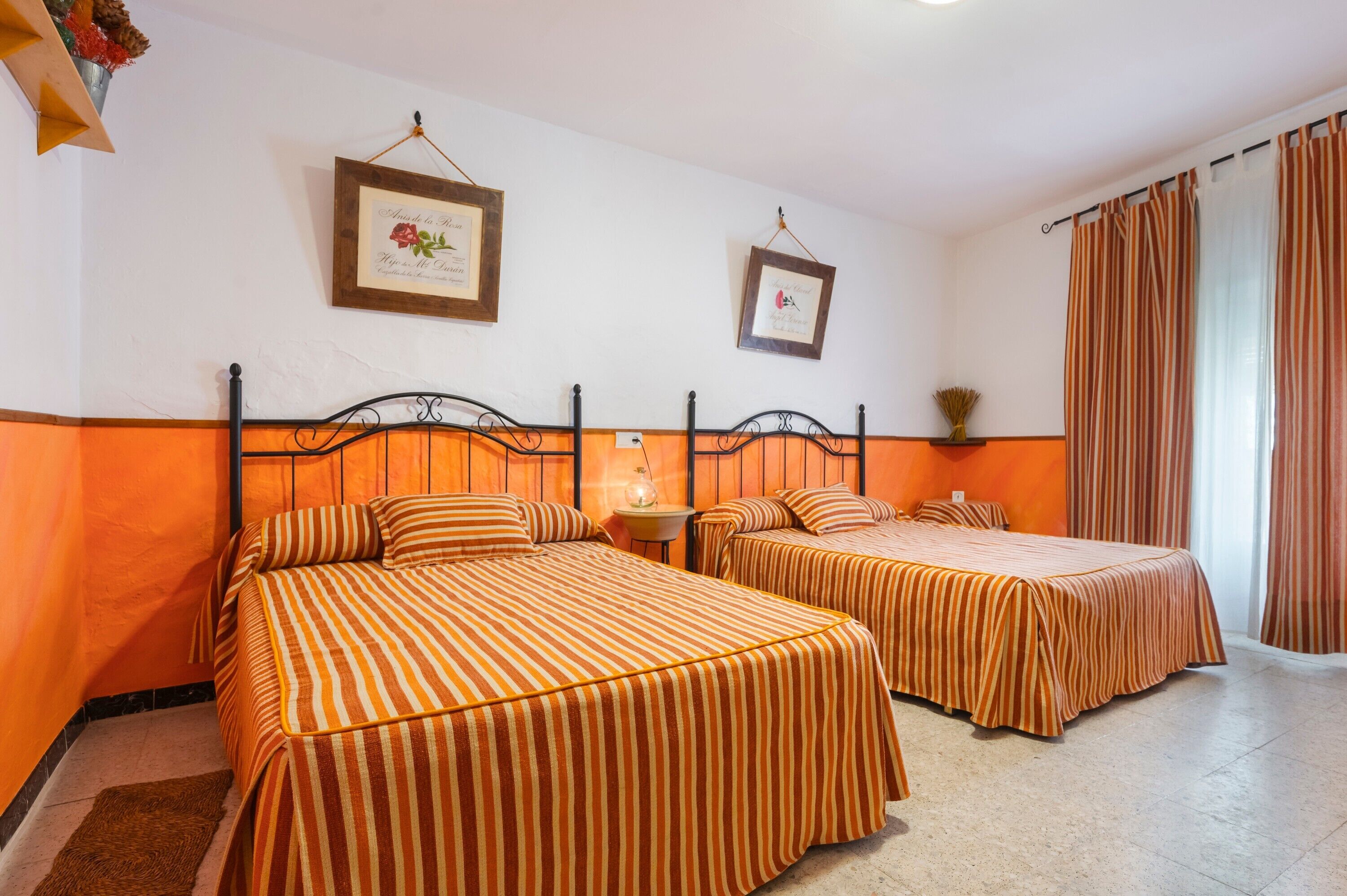 Une chambre d’hôtel avec deux lits, une petite table et deux tableaux encadrés au mur.