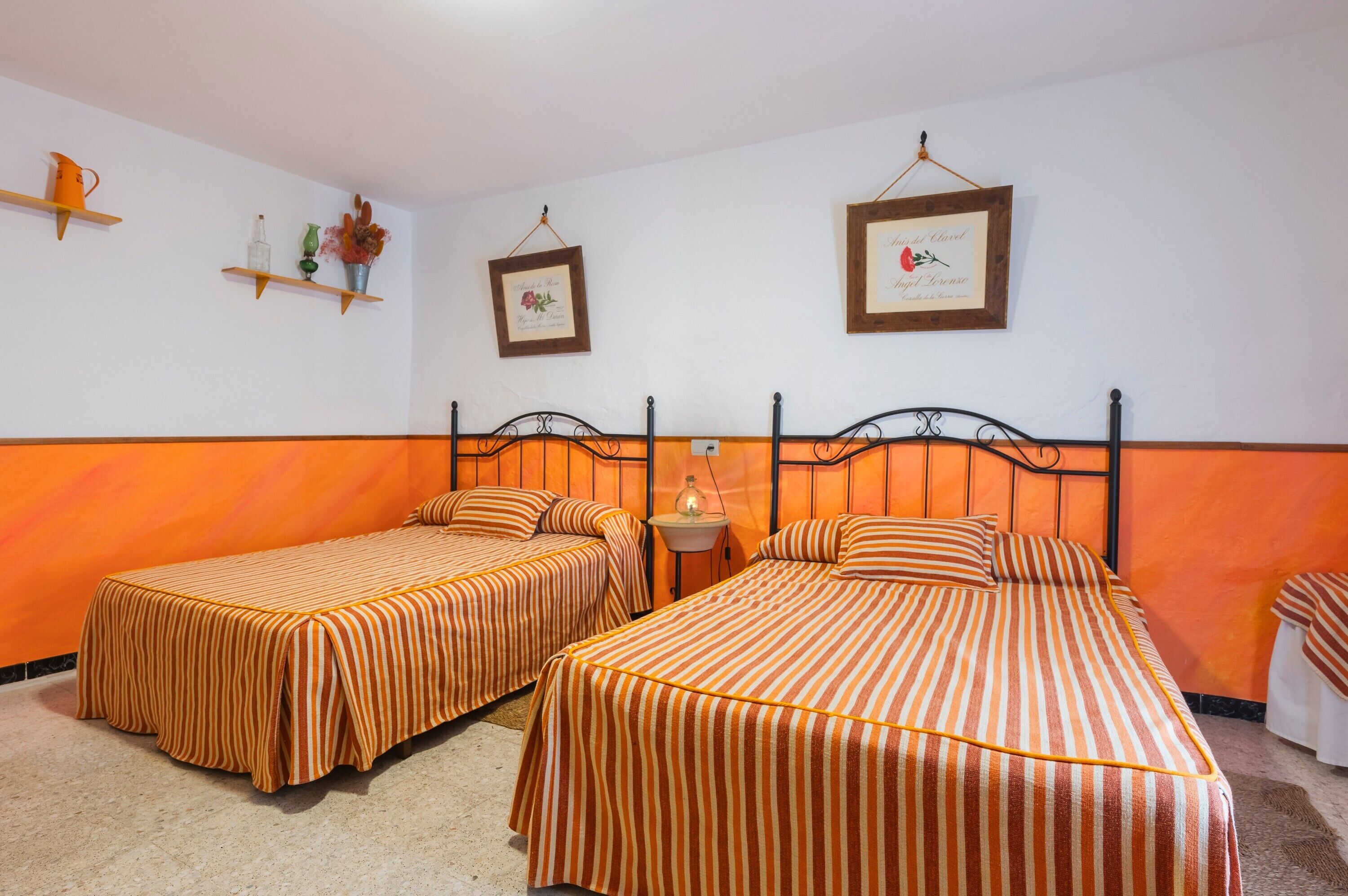 Una habitación de hotel con dos camas individuales, una mesita pequeña y estantes empotrados con objetos decorativos.