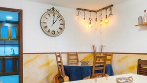 A dining area with a clock, hanging light fixtures, and a table with chairs. - Country House 'Fuente Nueva' with Balcony (Cazalla de la Sierra)