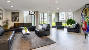 A spacious living area with leather sofas, a coffee table, and a large abstract painting.