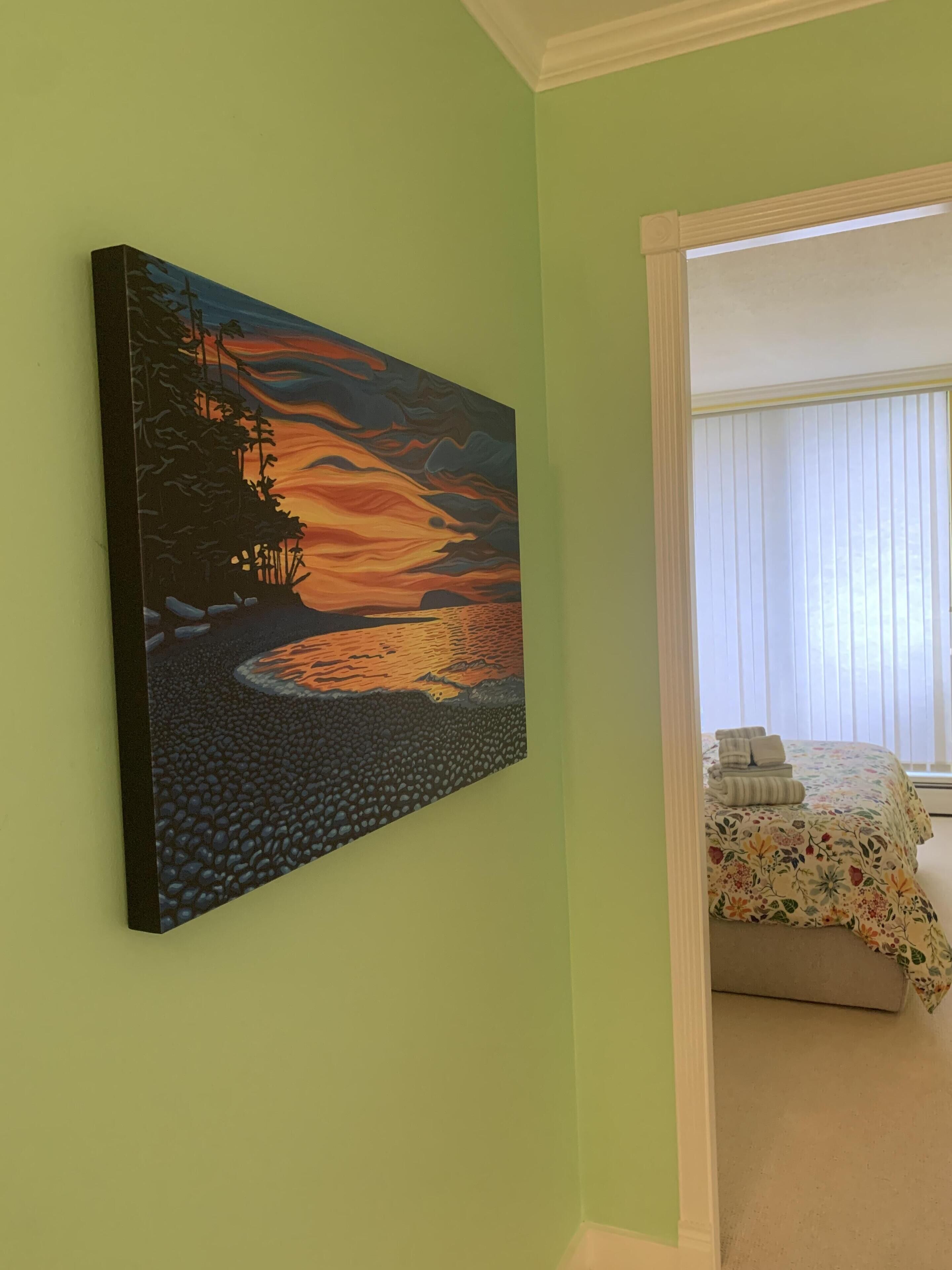 A room with a bed, a painting on the wall, and a window with blinds.