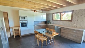 Une cuisine moderne avec une table à manger en verre, des chaises en bois et des appareils électroménagers intégrés.