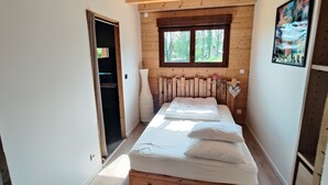 Une chambre à coucher avec une tête de lit en bois, une grande fenêtre et un lit recouvert de draps blancs.
