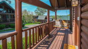 A wooden deck with a railing, a bench, and a welcome mat.