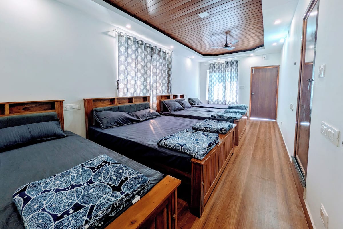 A hotel room with two beds, wooden headboards, a ceiling fan, and a window with curtains.
