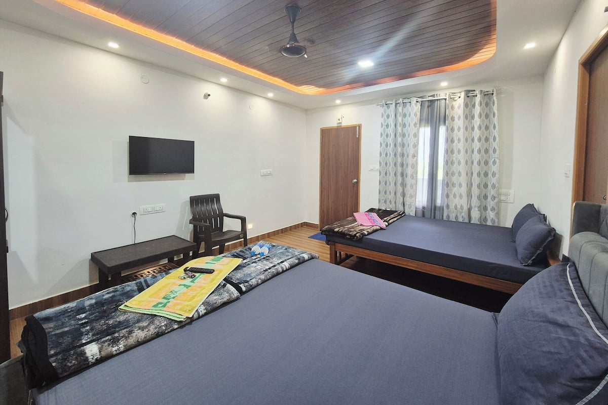 A hotel room with two beds, a TV, a desk, and a chair.