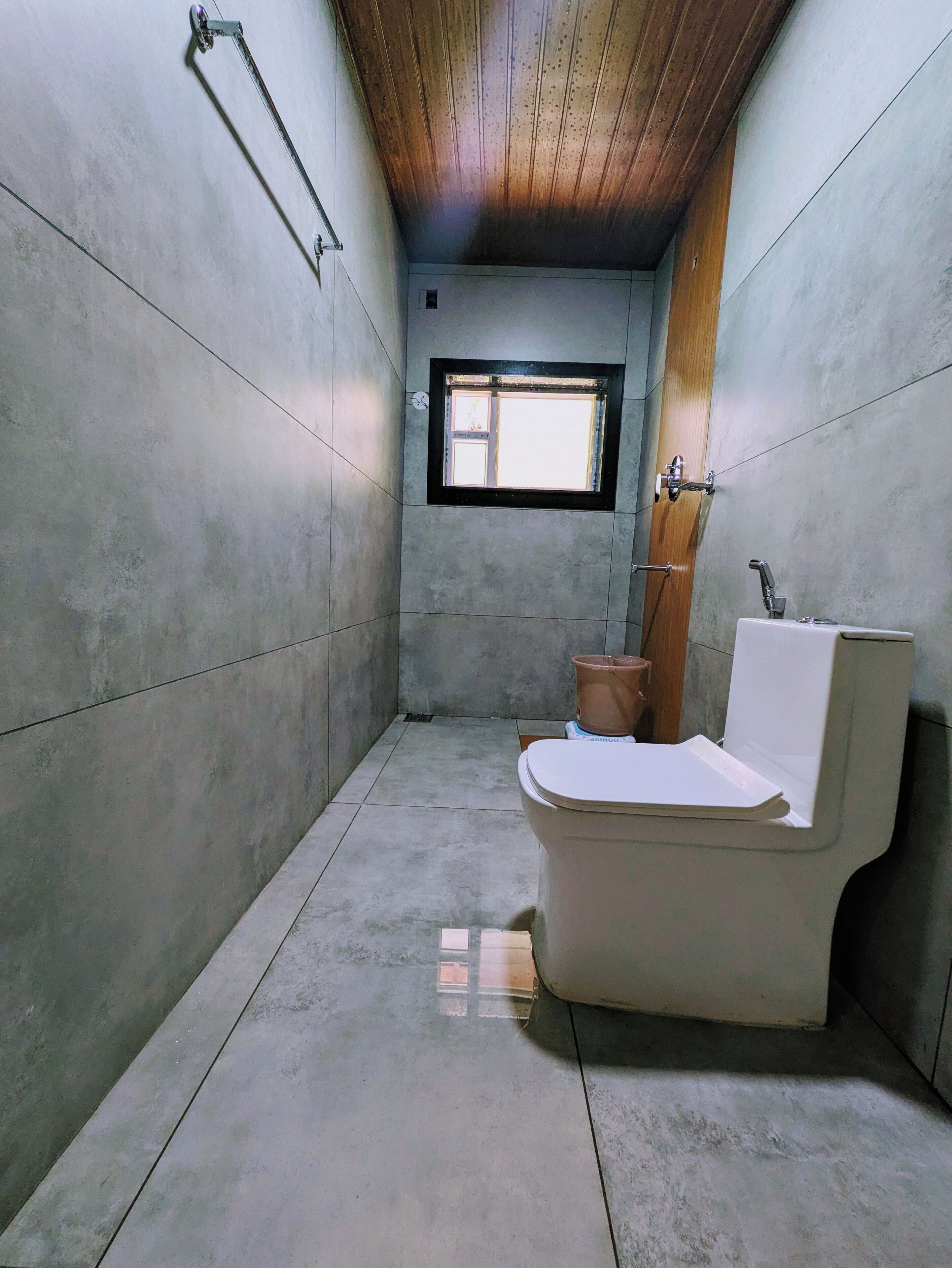 Une petite salle de bain étroite, avec des toilettes, un lavabo et une fenêtre.