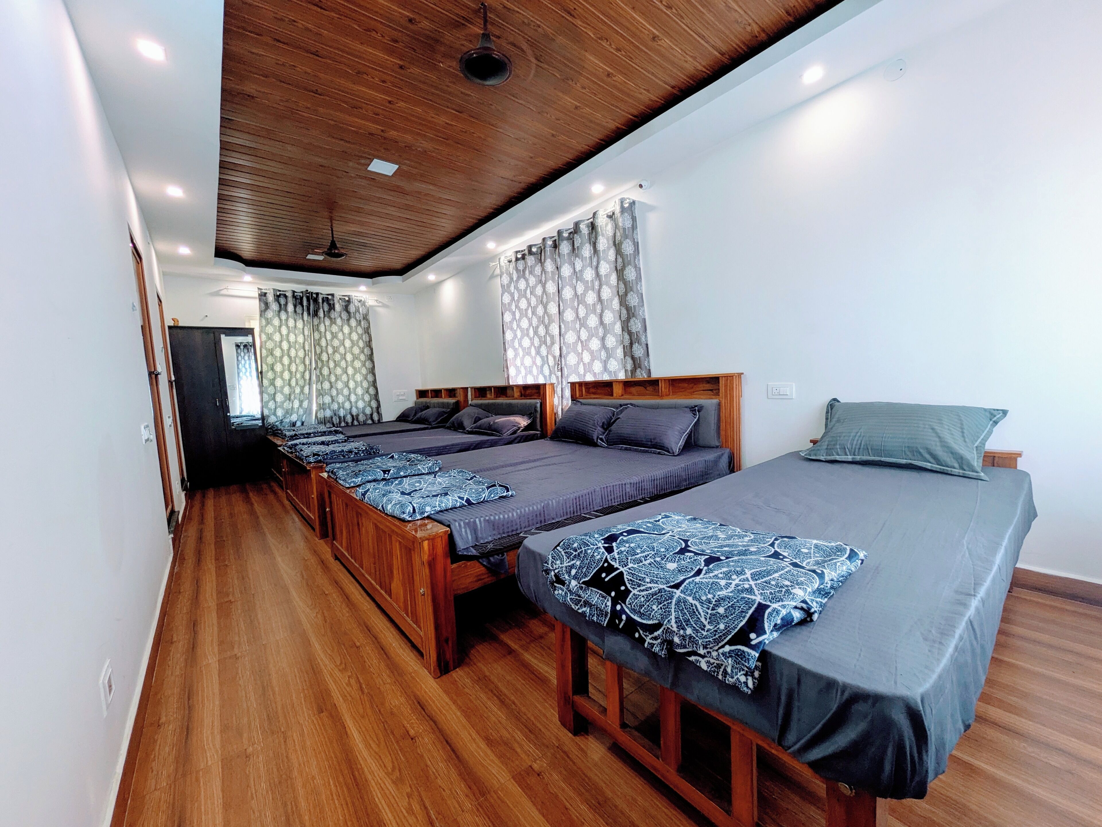 A room with two beds, wooden flooring, and a wooden ceiling.
