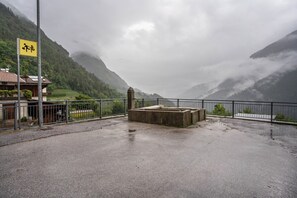 Une zone pavée avec une structure en béton, une clôture métallique et un bâtiment doté d’un toit en pente.