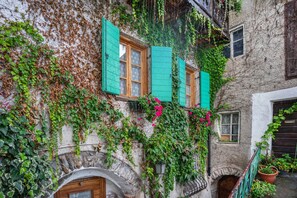 Un bâtiment aux murs recouverts de lierre, doté de volets en bois et d’une petite entrée en arc de cercle.