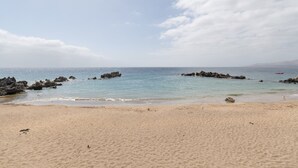 A beach with clear water, sandy shore, and rocky outcrops.