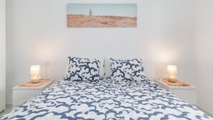 A bedroom with a bed, two bedside tables, a lamp on each, and a painting on the wall.