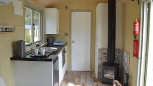 Une cuisine de taille réduite, équipée d’une cuisinière, d’un évier et de placards.