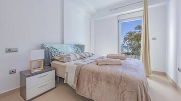 A modern bedroom with a bed, bedside table, and a window with a view.