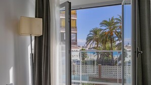A room with a view of palm trees and a building across the street.