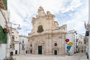 Un bâtiment historique à l’architecture riche et ornée, doté d’une entrée principale et orné d’une fresque représentant des fleurs sur l’un de ses murs latéraux.