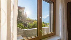 A window with a view of a balcony, a door, and a thermostat. - Cozy vacation apartment with unobstructed views of the surrounding mountains (Inzing)