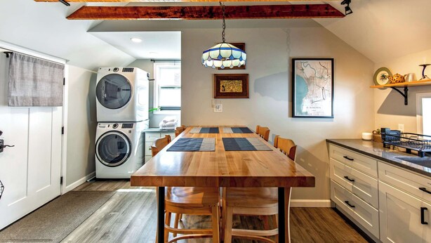 A kitchen with a wooden table, chairs, a washing machine, and a hanging light fixture. - Private Renovated Apt w/ Washer/Dryer near dwntwn! (Burlington)