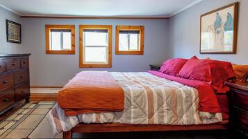Una camera da letto con un letto, due finestre, una cassettiera e un quadro appeso al muro.