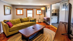 A living room with a sofa, a coffee table, a lamp, and a television. - Private Renovated Apt w/ Washer/Dryer near dwntwn! (Burlington)