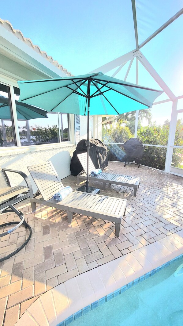 A poolside area with a covered seating area, a pool, and a view of the surrounding landscape. - Remodeled Waterfront Home w/ Heated Pool in Punta Gorda (Punta Gorda)