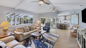 A spacious living area with a sofa, coffee table, and a dining area with a kitchen in the background. - Remodeled Waterfront Home w/ Heated Pool  in Punta Gorda (Punta Gorda)