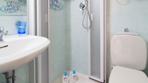 Une salle de bain équipée d’un lavabo, de toilettes, d’une douche et de deux flacons de savon pour les mains.