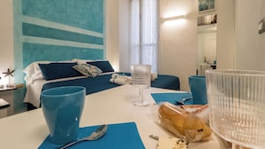 Une chambre d’hôtel avec un lit, une table à manger avec un petit pain, un verre à vin et un porte-clés.