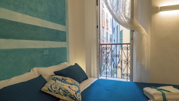 Une chambre à coucher avec un lit, des oreillers et une vue sur un balcon doté d’une balustrade.