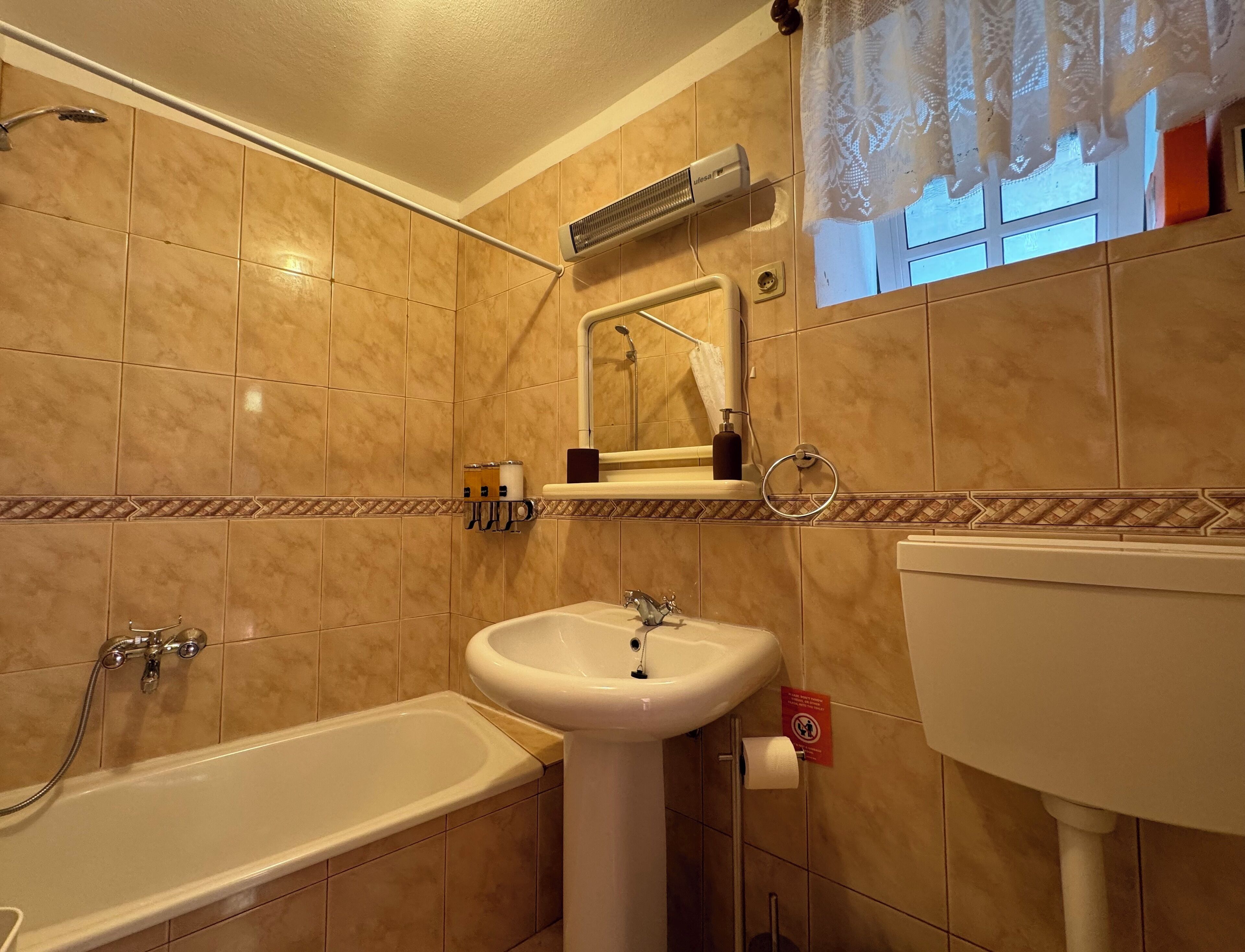 Bany amb banyera, un lavabo i un aparell d'aire acondicionat fixat a la paret.