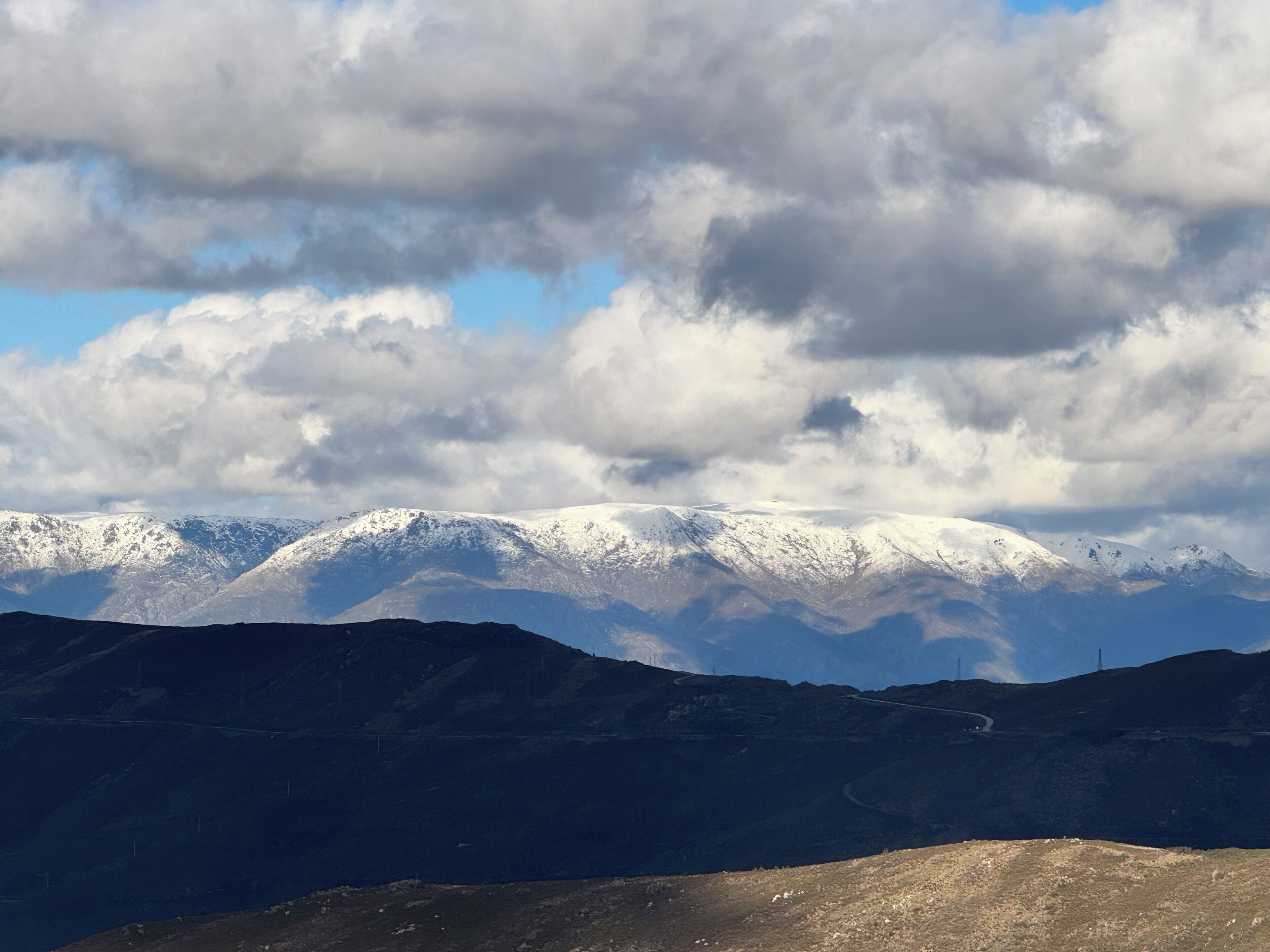 Eine gebirgige Landschaft mit schneebedeckten Gipfeln und blauem Himmel.