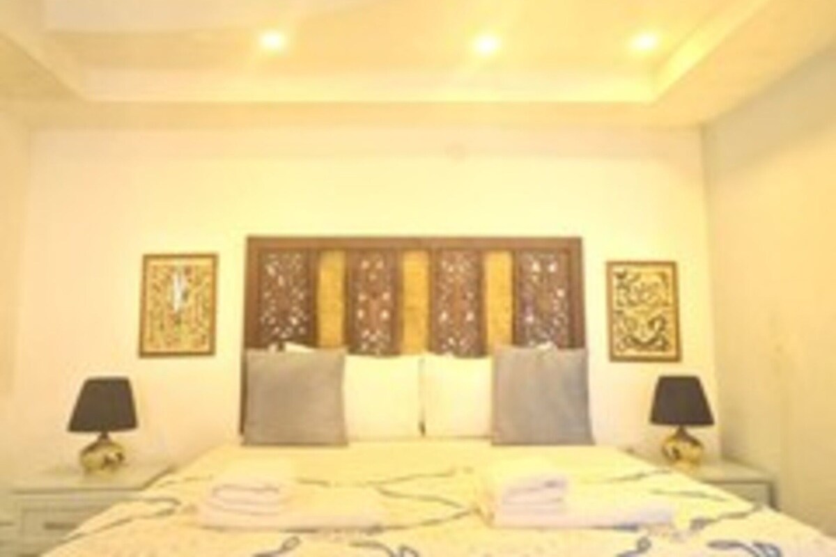 Habitación de hotel con cama, dos mesitas de noche y un cabecero decorativo.