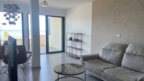 Ein modernes Wohnzimmer mit einer Couch, einem runden Couchtisch, einem Fernseher und einem Regal mit Dekoration.