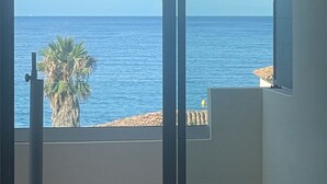 Ein Zimmer mit Meerblick, einer Palme und einem Balkon mit Geländer.