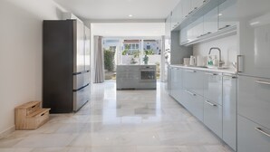 A modern kitchen with stainless steel appliances, a marble floor, and a view of the outdoor balcony.