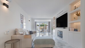 A modern living room with a sofa, a coffee table, a TV, and a fireplace.