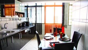A modern kitchen with a dining area, featuring a large window, a sink, and a dining table with chairs. - Apartment 'Fernandes' with Mountain View, Wi-Fi and Air Conditioning (Carvoeiro)