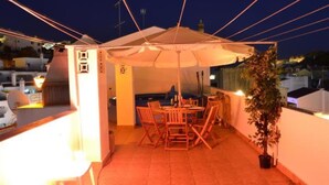 A rooftop patio with a table and chairs under a large umbrella, surrounded by a railing and a potted plant. - Apartment 'Fernandes' with Mountain View, Wi-Fi and Air Conditioning (Carvoeiro)