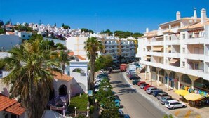 A coastal town with white buildings, a street with parked cars, and a clear blue sky. - Apartment 'Fernandes' with Mountain View, Wi-Fi and Air Conditioning (Carvoeiro)
