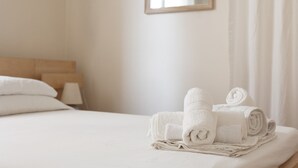 Een opgemaakt bed met opgerolde witte handdoeken en een houten hoofdbord.