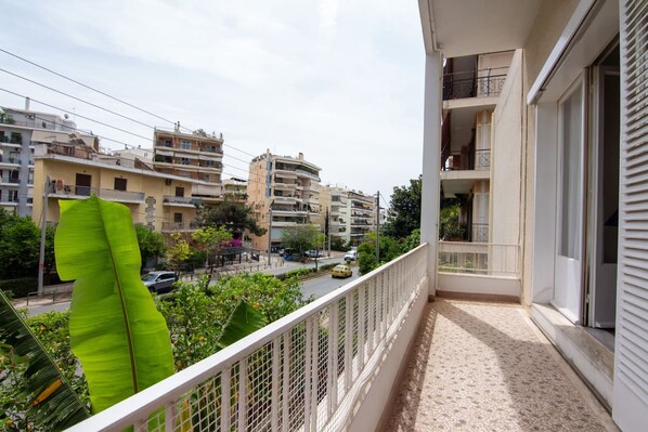 A balcony with a view of a cityscape, including multi-story buildings and a street with cars. - Cozy Apartment Next to Alimos Beach (Alimos)