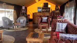 A cozy, tent-style room with leather sofas, patterned chairs, and a wooden coffee table. - Africa Safari Serengeti Kusini  (Bariadi)