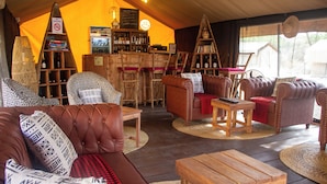 A cozy, rustic interior with leather sofas, wooden tables, and a bar area with a menu board. - Africa Safari Serengeti Kusini  (Bariadi)