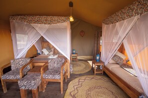 A cozy room with a bed, a sofa, and two chairs, all with patterned cushions. - Africa Safari Serengeti Kusini  (Bariadi)