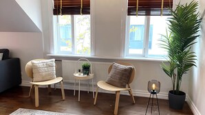 Eine gemütliche Sitzecke mit zwei Sesseln, einem kleinen Tisch mit Pflanzen, einer Stehlampe und einer großen Topfpflanze.
