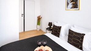 A bedroom with a bed, a bedside table, a lamp, a vase with flowers, and a framed picture on the wall. - Lumina 3-room apart on Drewnowska (Lódz)
