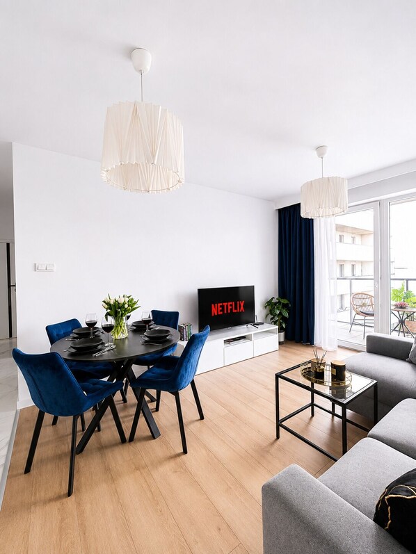 A modern living room with a dining area, a flat-screen TV, and a sofa. - Lumina 3-room apart on Drewnowska (Lódz)
