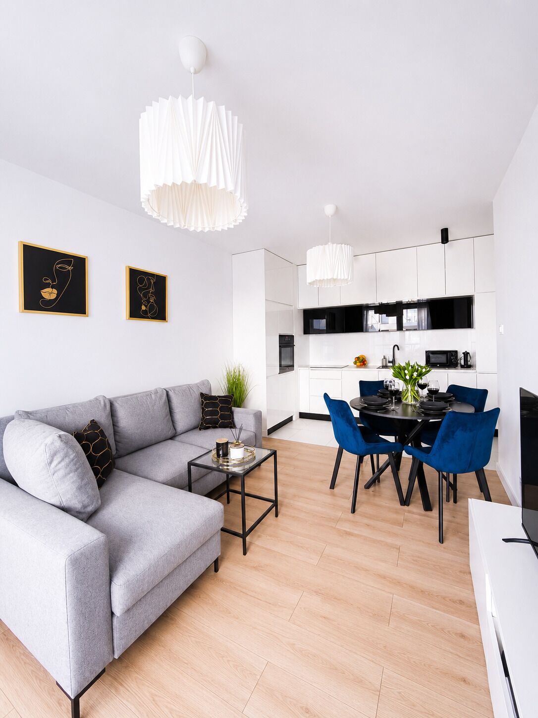 A modern living room with a grey sofa, a coffee table, and a dining area with blue chairs.